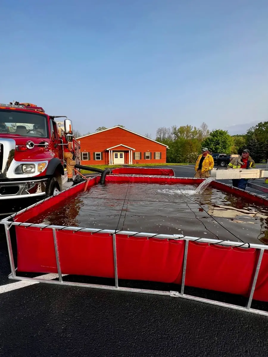 Ghent volunteers setting up a folding portable drop tank with Tanker 22-35 outside Station 1