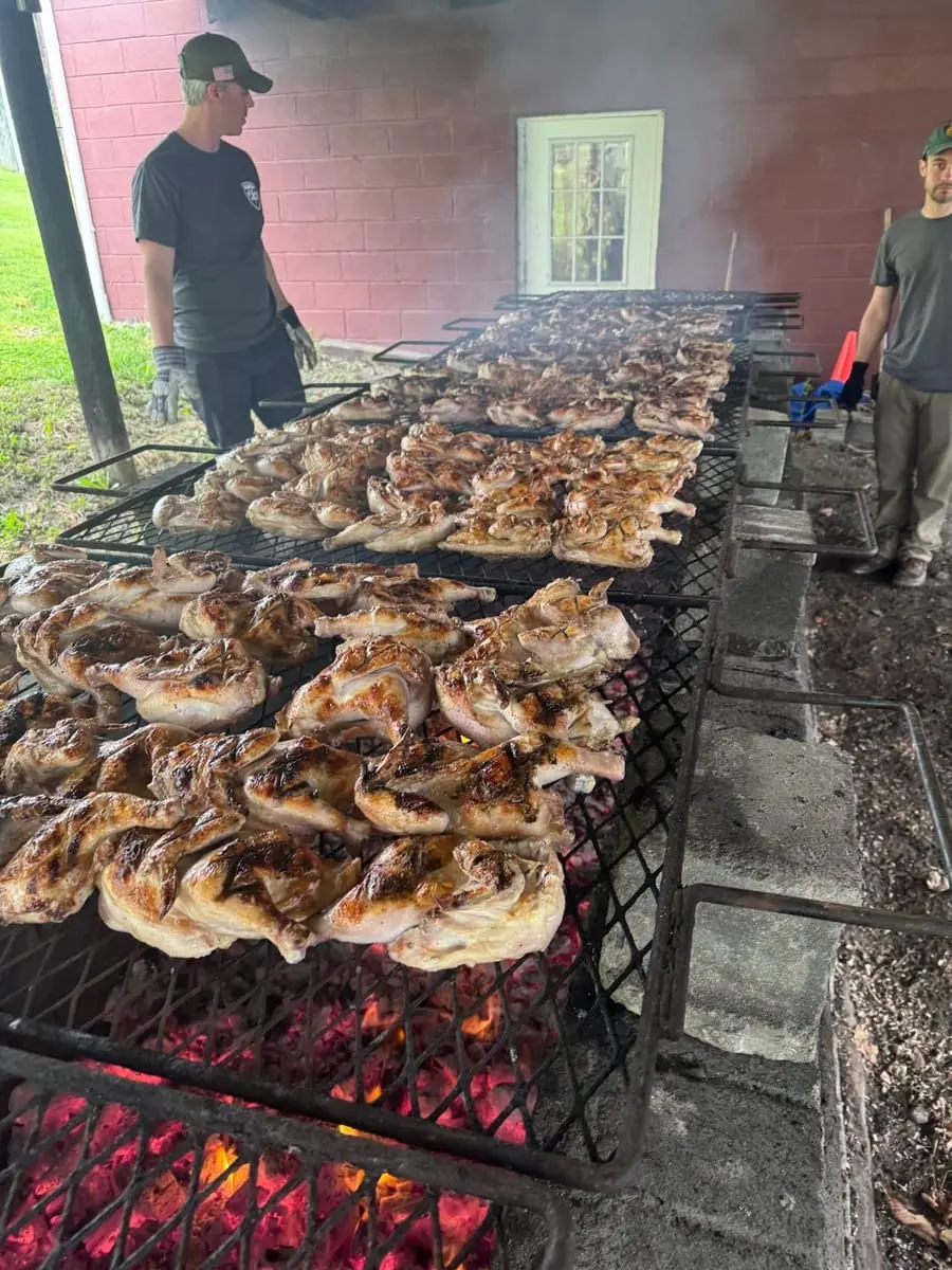 Rows of chicken halves grilling over charcoal at the Ghent Volunteer Fire Company Chicken BBQ