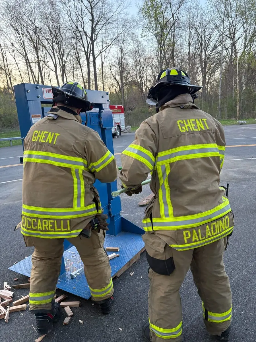 Firefighters practicing forcible entry techniques on a steel training door prop at Station 1